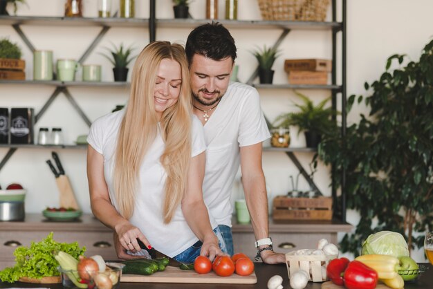 Mens die haar groenten van het vrouwenknipsel op keukenteller omhelst