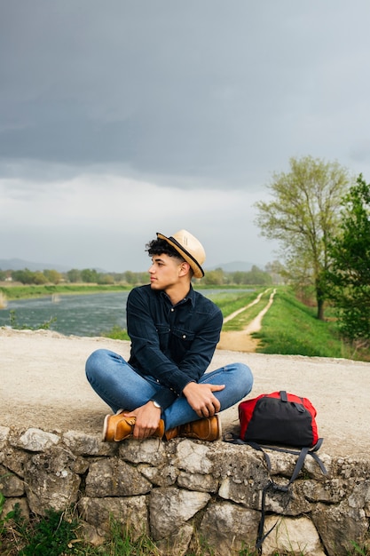 Gratis foto mens die hoedenzitting dragen dichtbij mooie rivier