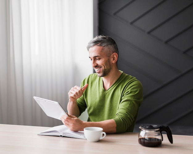 Gratis foto mens die in groen overhemd de tablet bekijkt