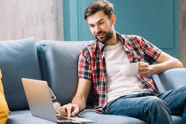 Mens die laptop drinkt en met behulp van