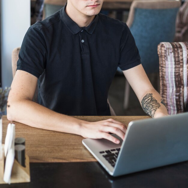 Mens die laptop in koffie met behulp van