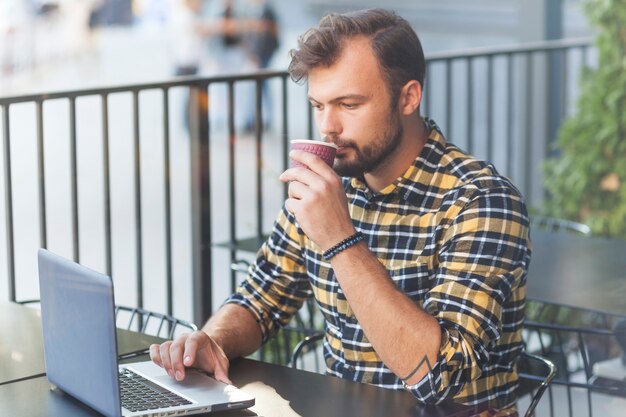 Mens die laptop in koffiewinkel met behulp van