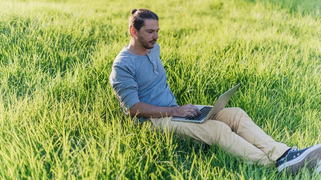 Mens die laptop in park met behulp van