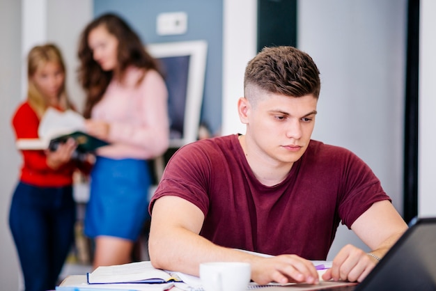 Gratis foto mens die met laptop bij bureau bestudeert