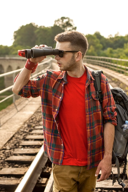 Gratis foto mens die met rugzak met binoculair in afstand kijkt