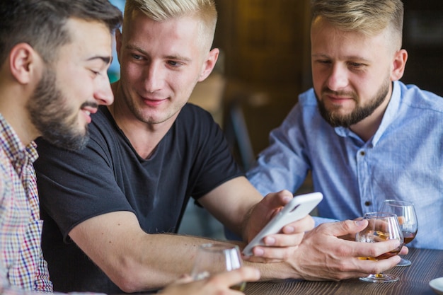 Mens die mobiele telefoon toont aan zijn mannelijke vrienden