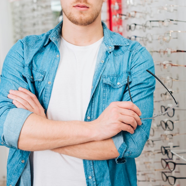 Gratis foto mens die nieuwe glazen zoekt bij optometrist