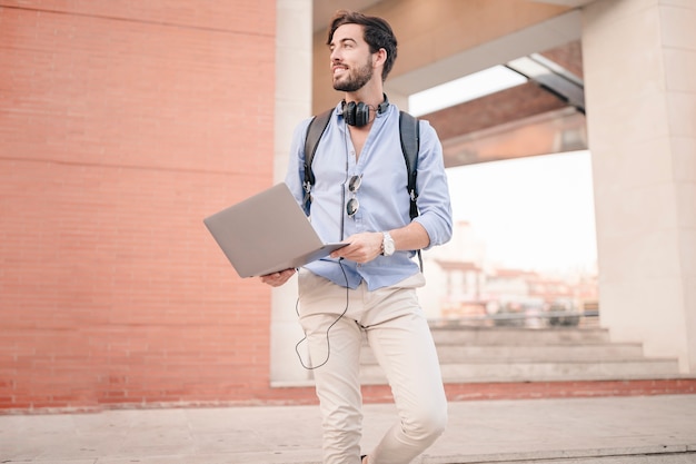 Gratis foto mens die onderaan trap met laptop loopt