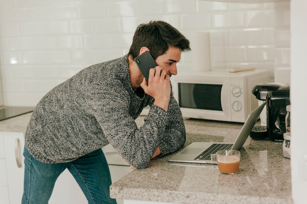 Mens die op telefoon spreekt terwijl het gebruiken van laptop