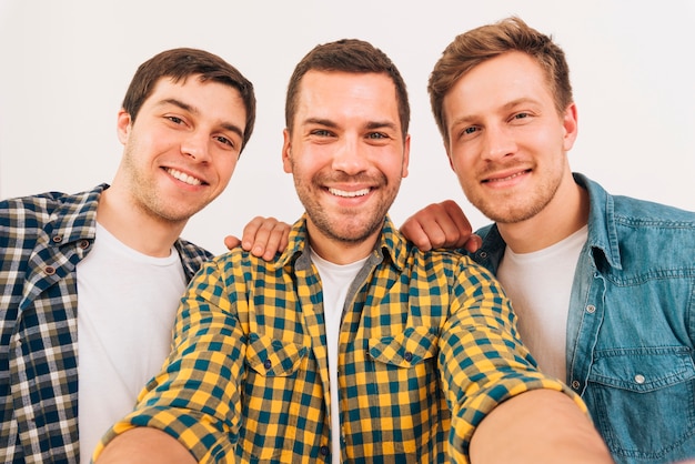 Mens die selfie met zijn vriend nemen tegen witte achtergrond