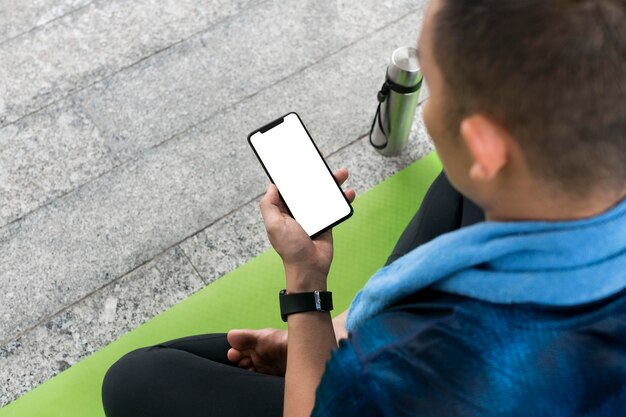 Mens die smartphone controleert alvorens wat yoga te doen