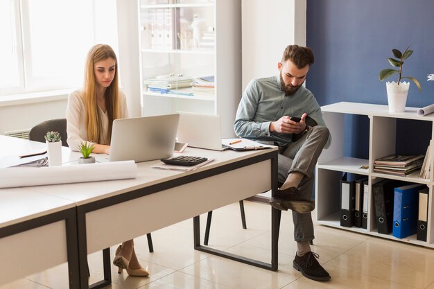 Mens die smartphone met behulp van dichtbij collega