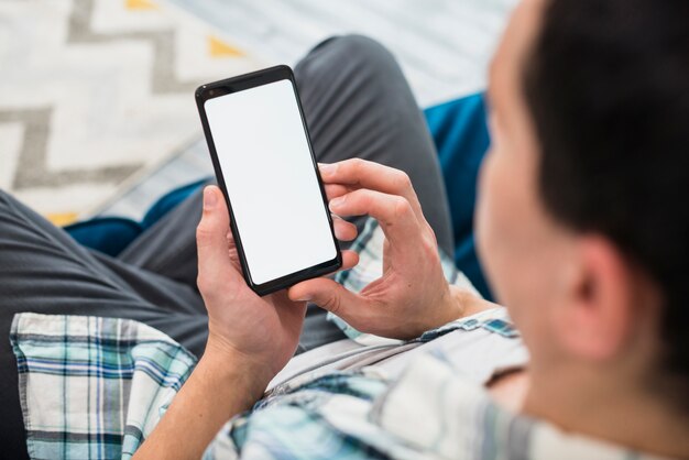 Mens die smartphone op sofa gebruikt