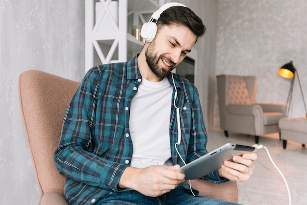 Mens die tablet gebruikt en aan muziek luistert