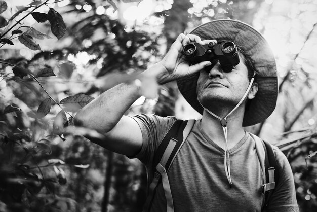 Mens die verrekijkers in het bos met behulp van