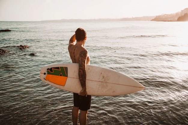 Mens die zich met surfplank in overzees bevindt