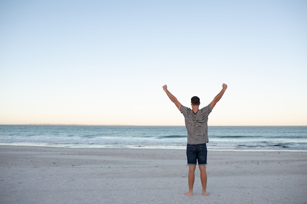 Mens die zich met wapens uitgestrekt op het strand bevindt