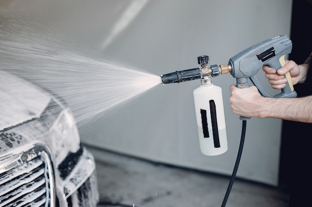 Mens die zijn auto in een garage wast