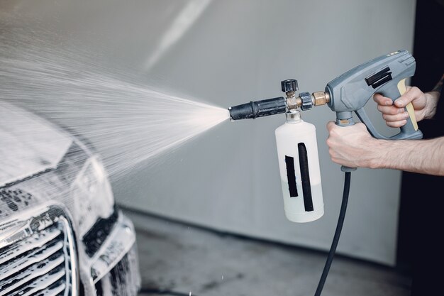 Mens die zijn auto in een garage wast