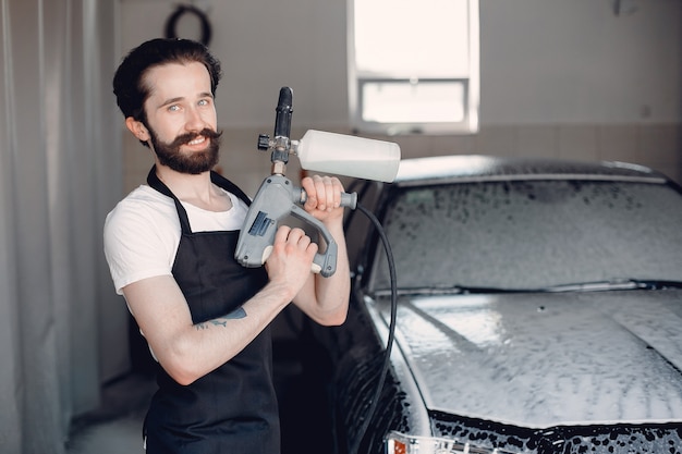 Mens die zijn auto in een garage wast