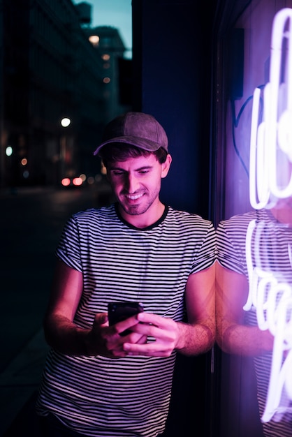 Mens die zijn telefoon en glimlach bekijkt