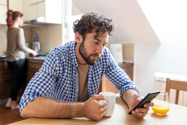 Mens die zijn telefoon in de keuken bekijkt