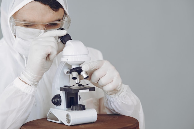 Mens in beschermend kostuum en glazen die bij laboratorium werken