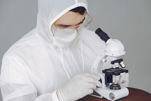 Mens in beschermend kostuum en glazen die bij laboratorium werken