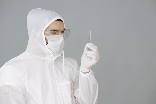 Mens in beschermend kostuum en glazen die bij laboratorium werken