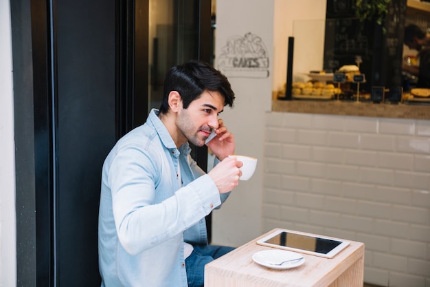 Mens in koffie die op telefoon spreekt