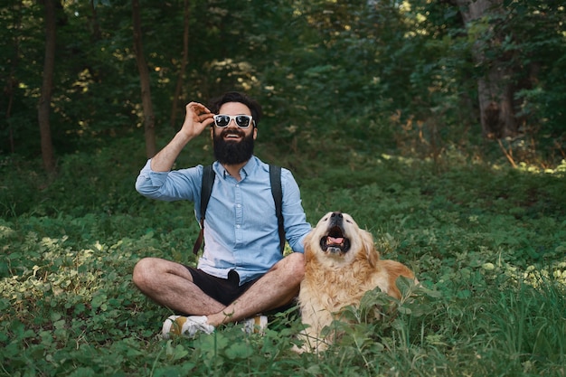 Gratis foto mens in vrijetijdskleding en zijn hond stellen die aan camera kijken