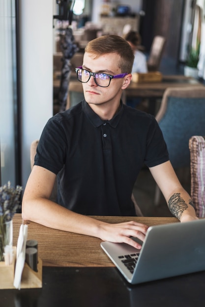 Mens in zwarte die aan laptop in koffie werkt