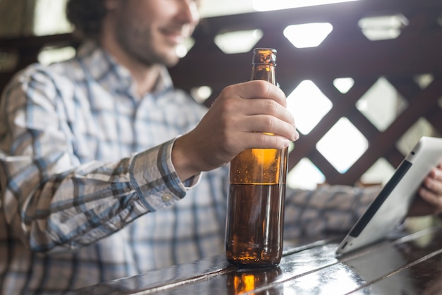 Gratis foto mens met bier doorbladert tablet bijsnijden