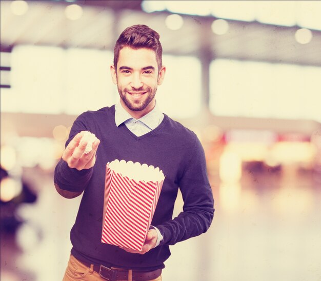 Mens met popcorn in één hand en een pakket in de andere