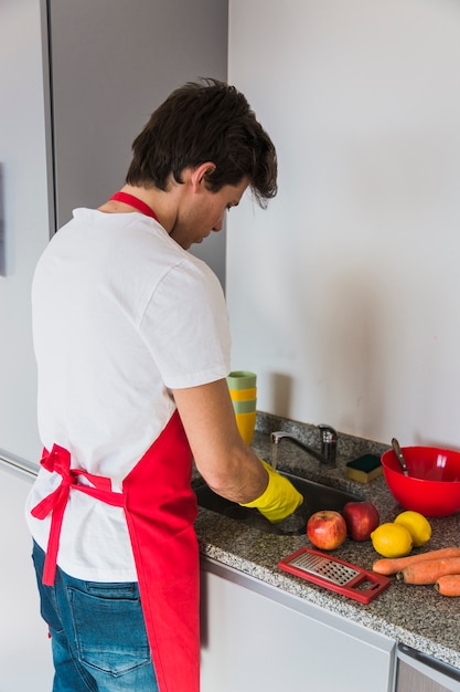 Mens met rode schort die in keuken werkt