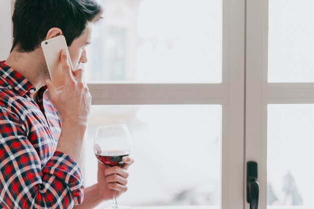 Mens met rode wijn sprekende telefoon