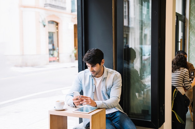 Mens met smartphonezitting in koffie