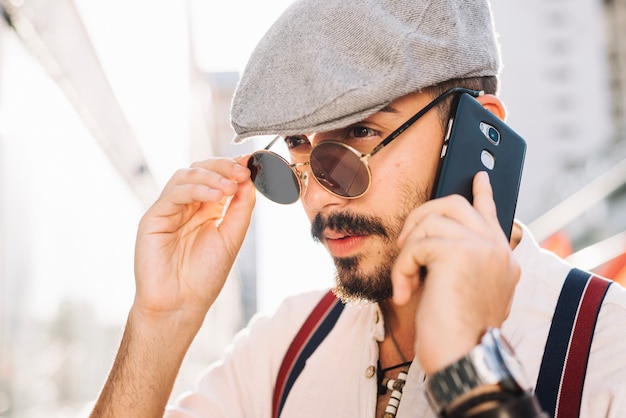 Mens met telefoon die zonnebril opstijgt