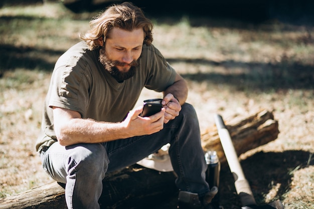 Mens met telefoon door vreugdevuur in bos