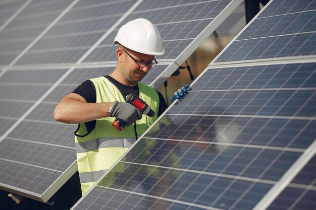 Mens met witte helm dichtbij een zonnepaneel