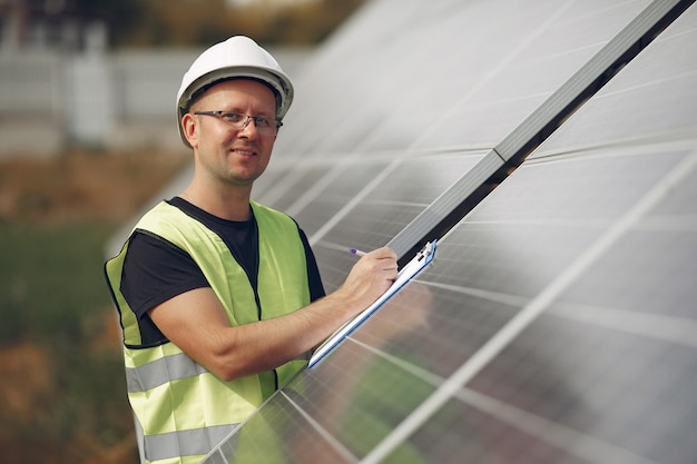 Mens met witte helm dichtbij een zonnepaneel