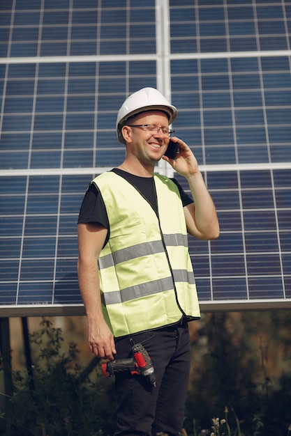 Mens met witte helm dichtbij een zonnepaneel