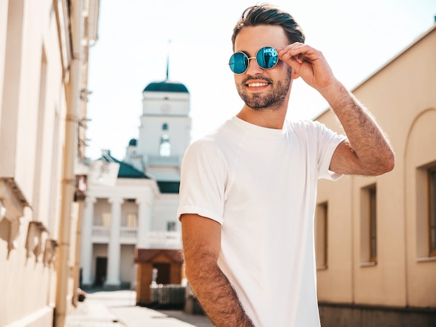 Mens met zonnebril die het witte t-shirt stellen dragen