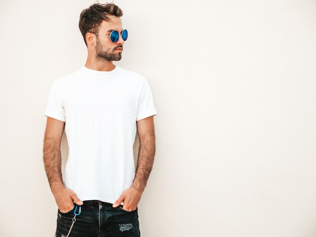 Mens met zonnebril die het witte t-shirt stellen dragen