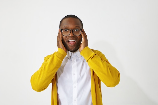 Menselijke gezichtsuitdrukkingen, emoties, gevoelens, reactie en houding. foto van knappe grappige afro-amerikaanse man met stijlvolle bril, mond openen, opgewonden met positief goed nieuws