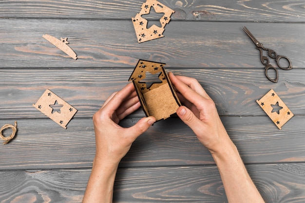 Menselijke hand die huis van karton op houten bureau maakt