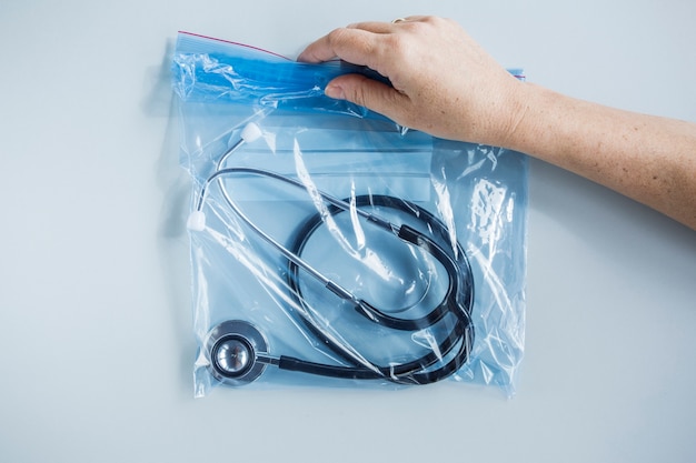Menselijke hand met zip lock plastic zak met stethoscoop