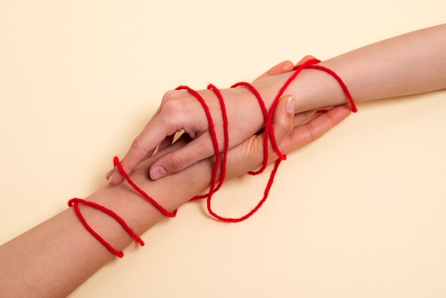 Gratis foto menselijke handen verbonden met rode draad