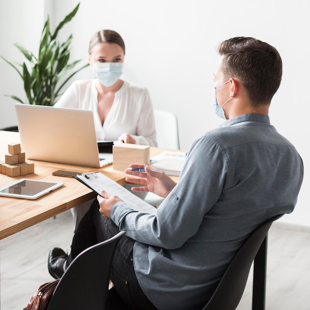 Mensen aan het werk op kantoor tijdens pandemie die medische maskers dragen