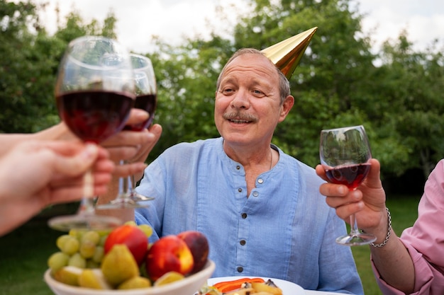 Gratis foto mensen buiten in de tuin vieren een oudere verjaardagsfeestje